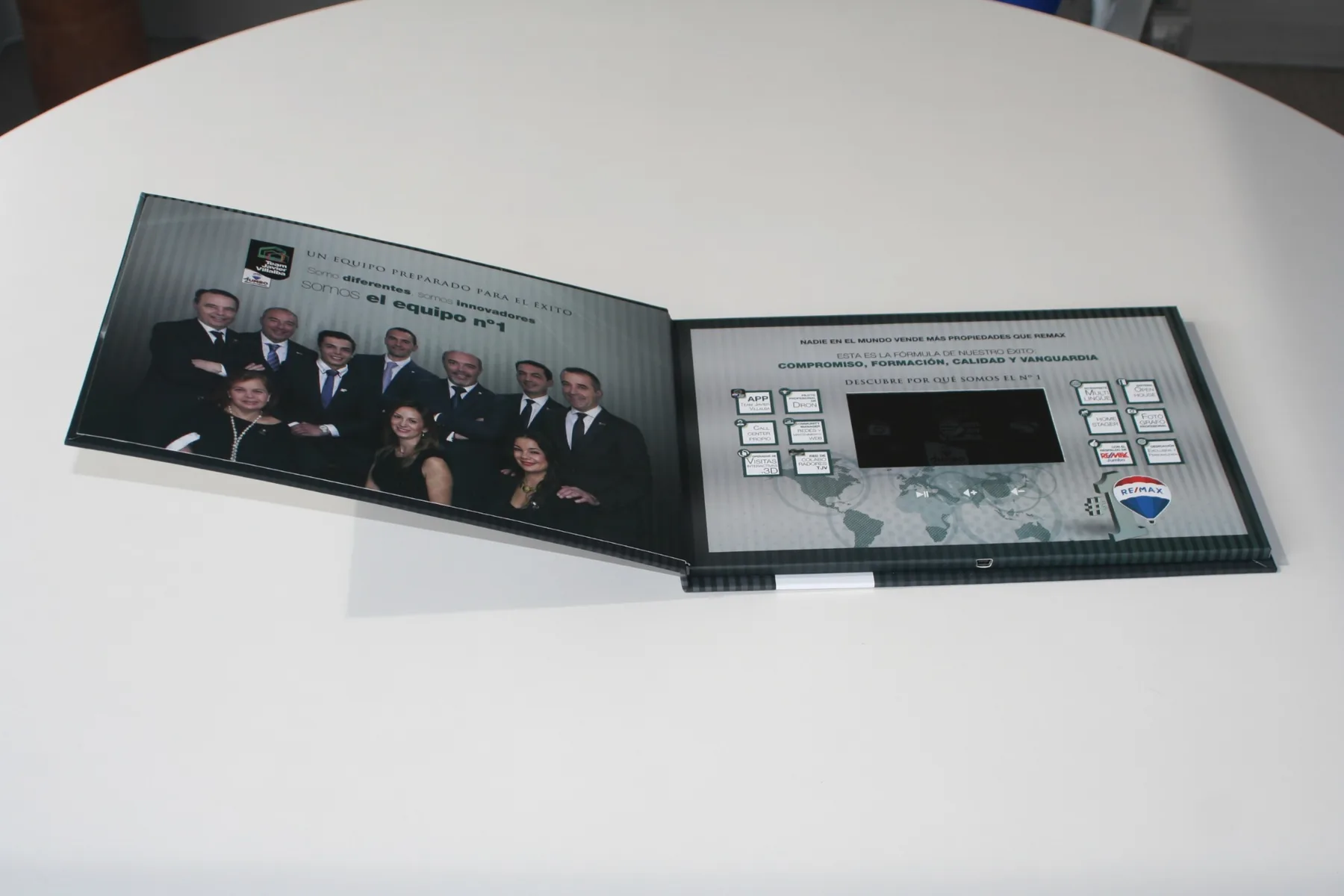 Videocarpeta RE/MAX abierta: foto de equipo y pantalla con teclado